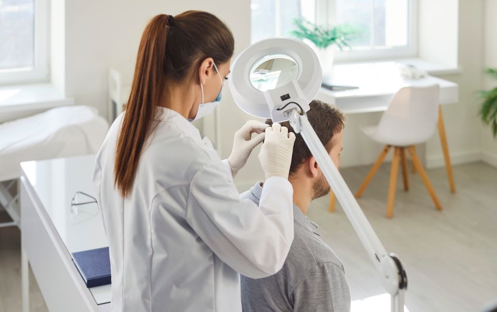 Portrait Of Young Female Doctor Examining Male