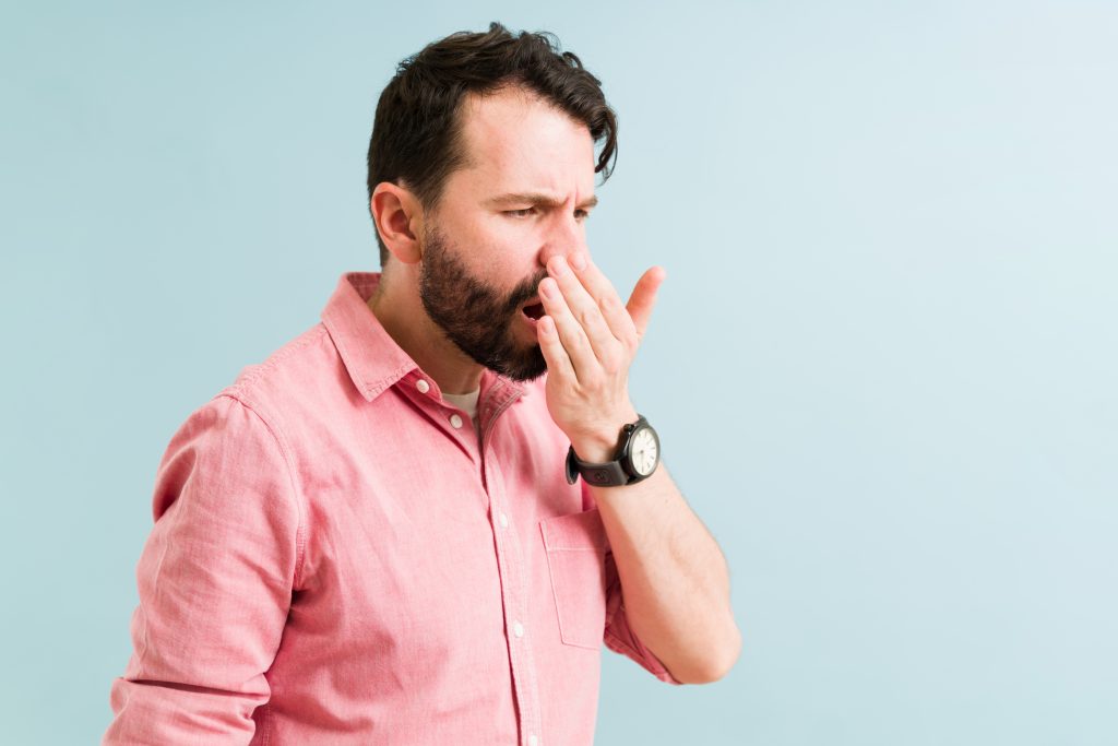 Man smelling his breath 