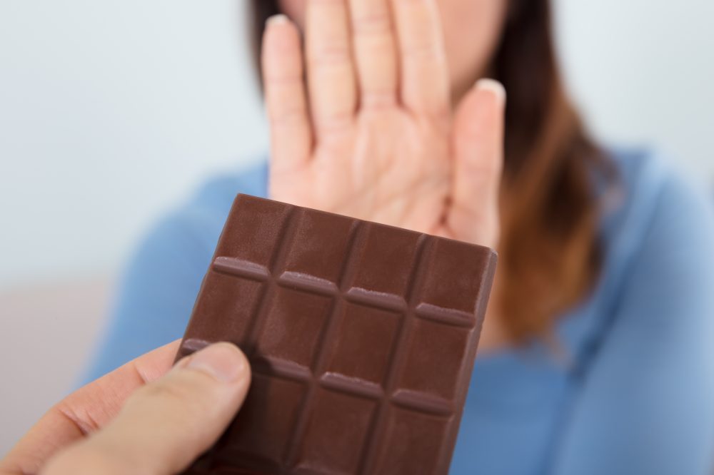 Woman rejecting a chocolate bar  and Does Chocolate Have Caffeine?