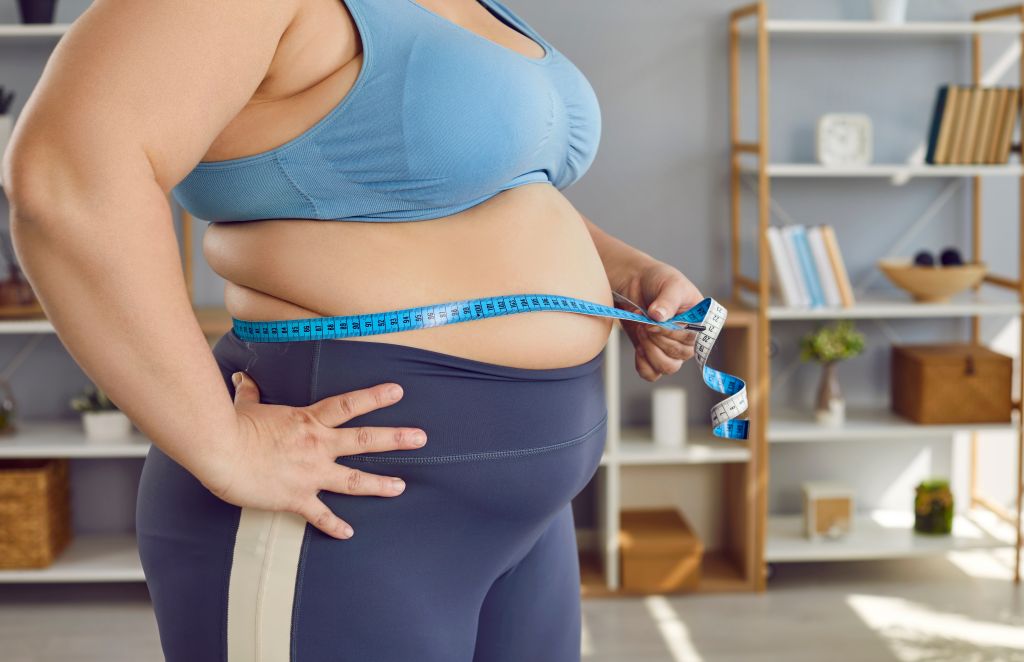 Overweight woman measuring her stomach