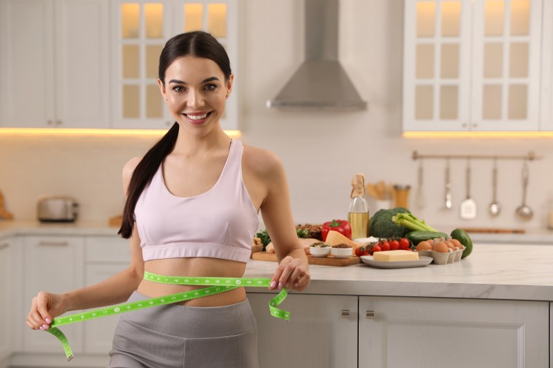 Happy woman measuring her waist