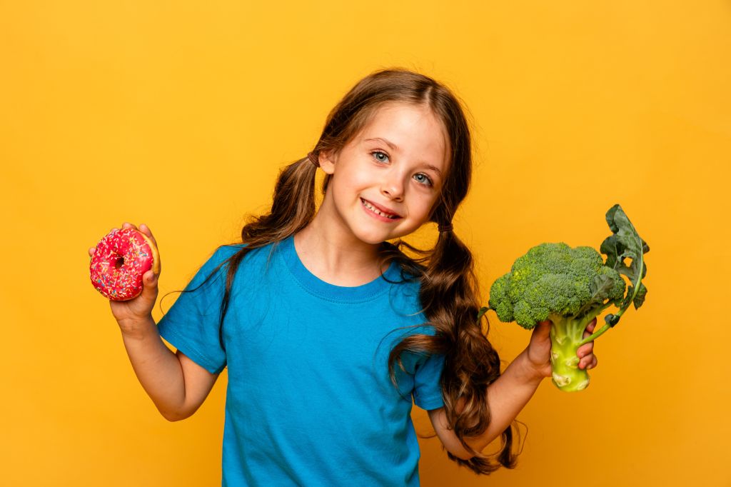 Girl holding doughnut and broccoli 