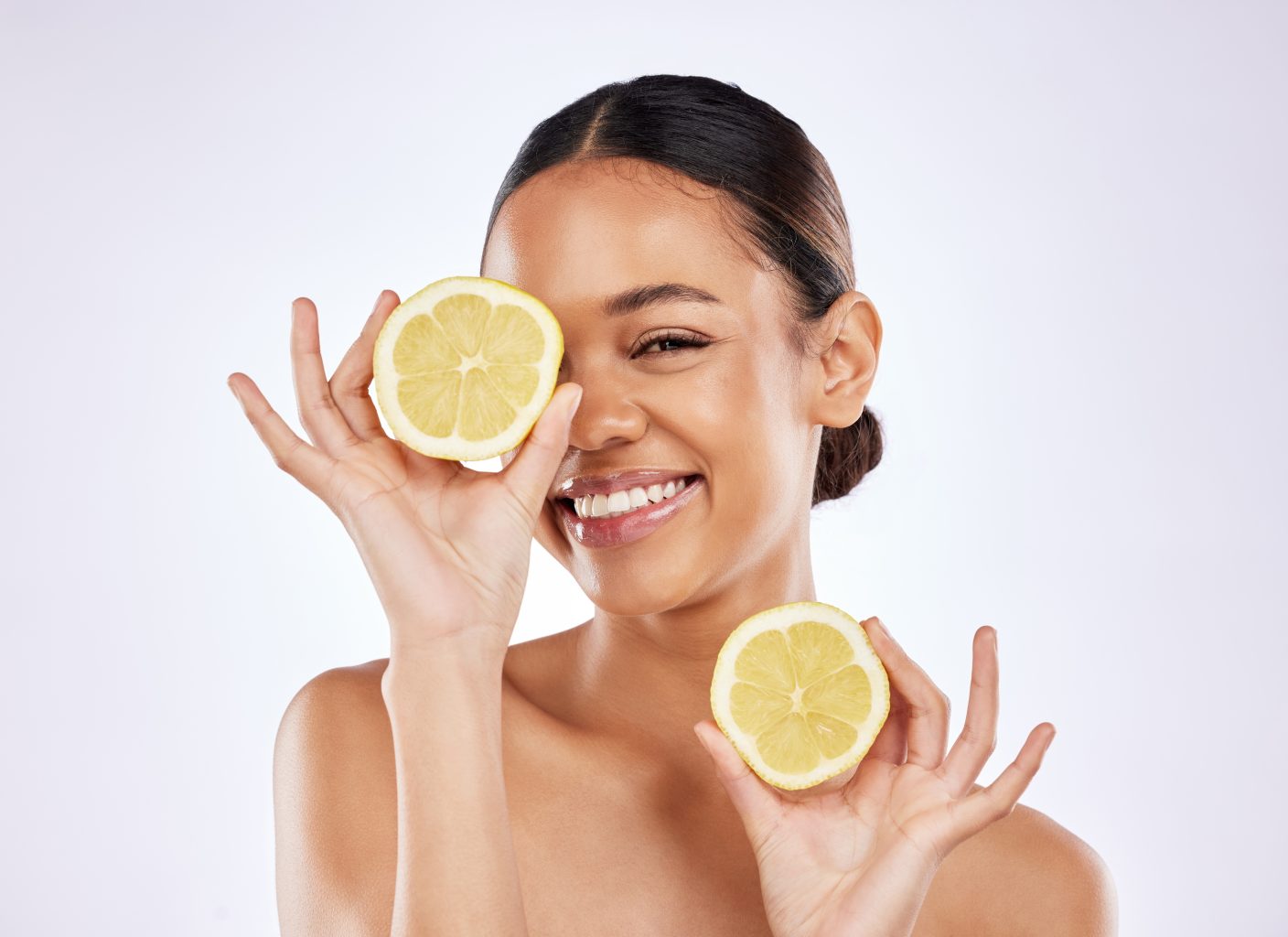 Woman holding lemons in front of her eyes.