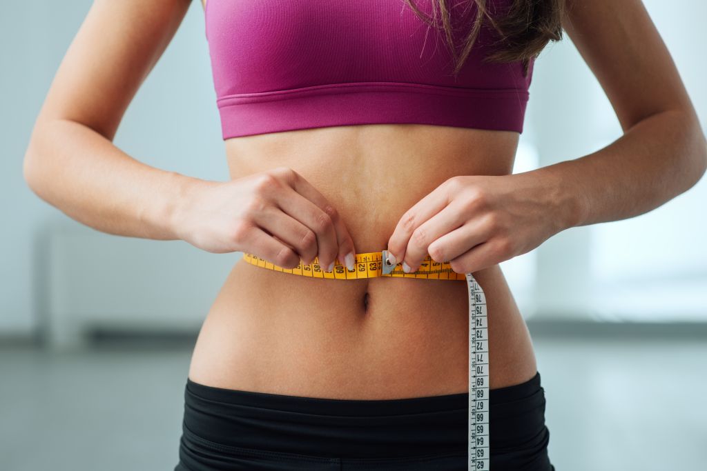 Fit woman measuring waistline