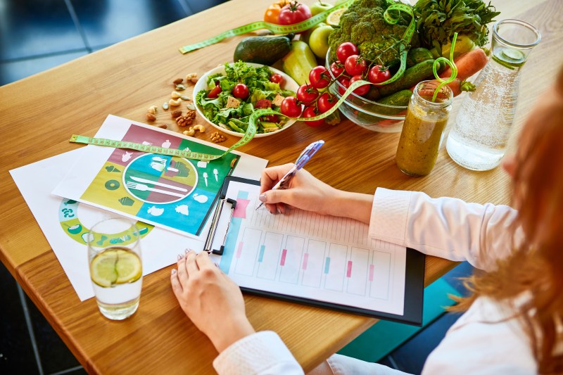 Nutritionist planning meals with vegetables and diet charts