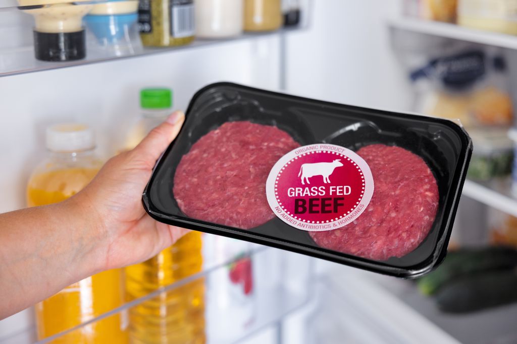 a hand holding a tray of grass-fed meat