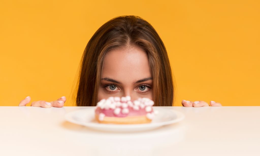 Hungry woman peeking at a donut