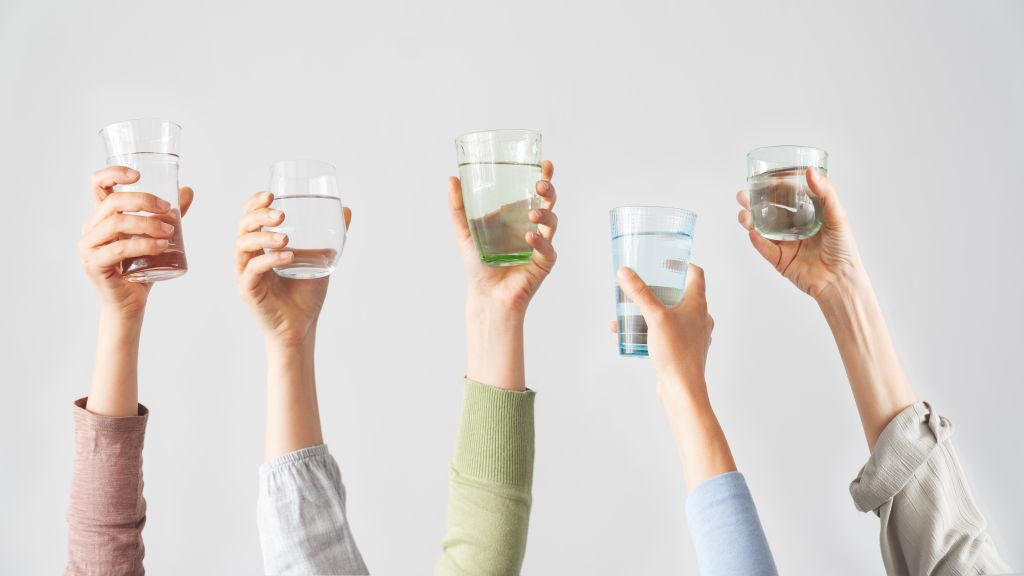 Different hands holding water glasses